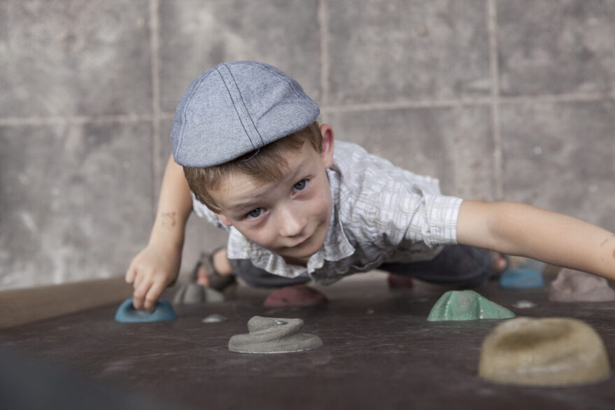 Junge klettert an einer Kletterwand