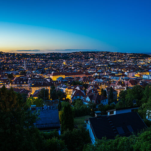 Der Stuttgarter Talkessel in der Abenddämmerung mit vielen beleuchteten Häusern und Straßen.