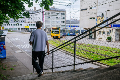 Eine Personen läuft ein Stäffele nach unten, im Hintergrund fährt die Stuttgarter Stadtbahn.
